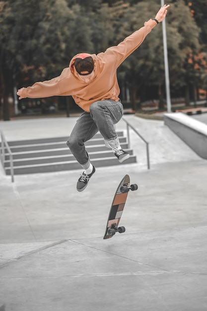 Guy bouncing high in air and skateboard falling below