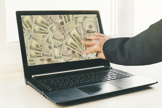 Guy or businessman holding buck money in his hand Laptop in the background