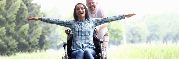 Guy carries joyful woman in wheelchair closeup