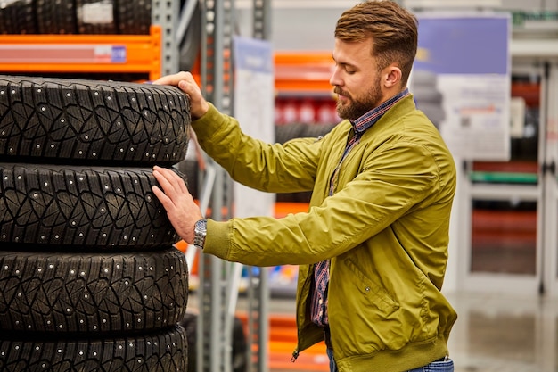 Guy choosing car tire in store, caucasian male want to buy wheels for automobile, examine the assortment