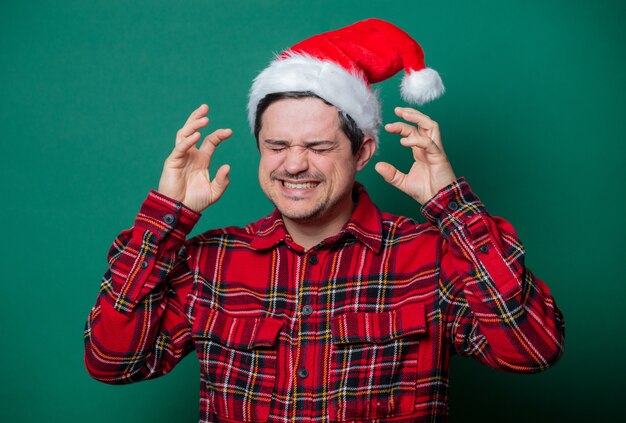 Guy in Christmas hat and tartan shirt on green