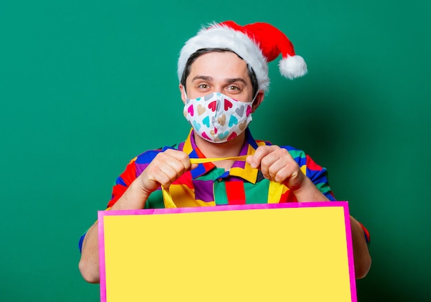 Guy in Christmas hat and vintage shirt with shopping bags on green