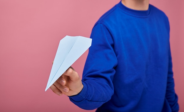 guy in dark blue sweater is standing on pink with blue paper airplane