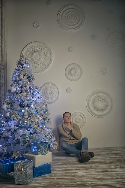 guy decorates the Christmas tree / man model in the New Year's studio