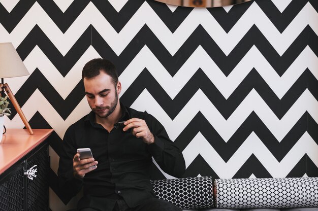 Guy drinking first morning coffee while checking emails on mobile