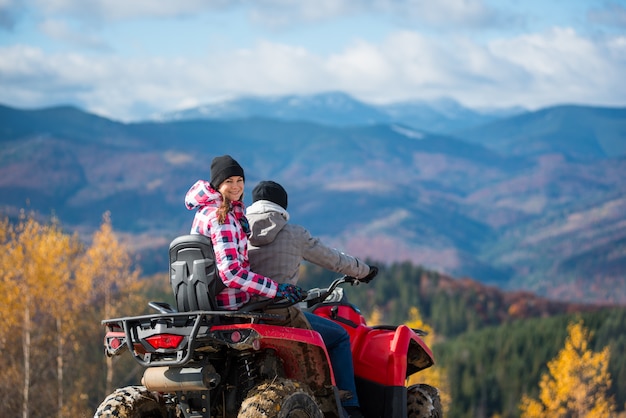 Guy driving ATV, girl sitting behind him and turned around