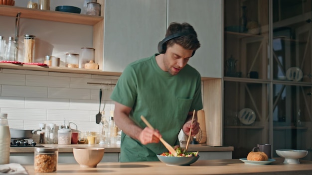 Photo guy earphones preparing food dancing along favorite song at kitchen closeup