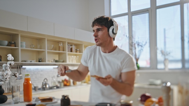 Guy earphones preparing food dancing home close up man listening music kitchen