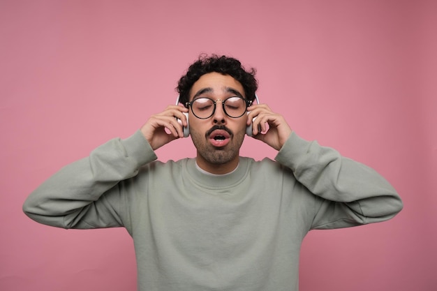 guy emotionally listening to music in his headphones with his hands on the headphones