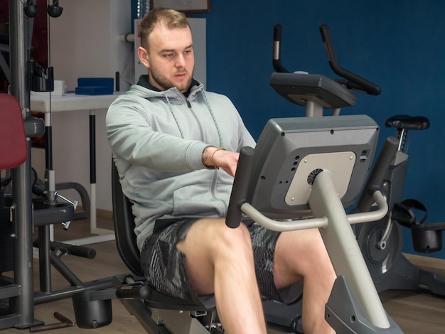 Guy on an exercise bike in the gym Fitness workout and healthy lifestyle