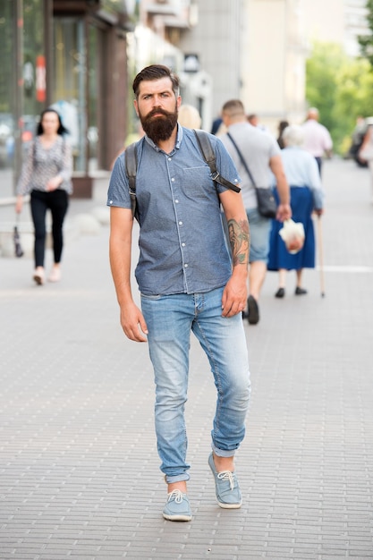 Guy exploring city Comfortable tourism Summer vacation Sightseeing concept Backpack for urban travelling Hipster wearing backpack urban street background Bearded man travel with backpack