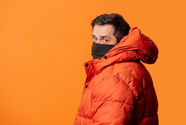 Ragazzo in maschera e piumino sull'arancio