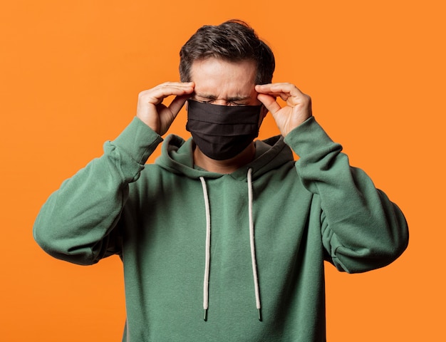 Guy in face mask and green hoodie on orange