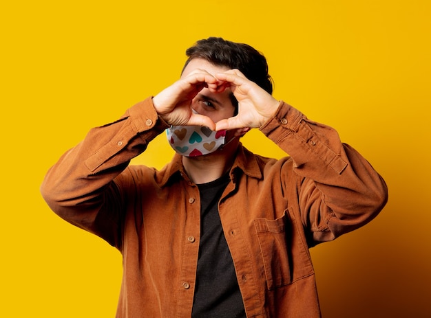 Guy in face mask show heart gesture