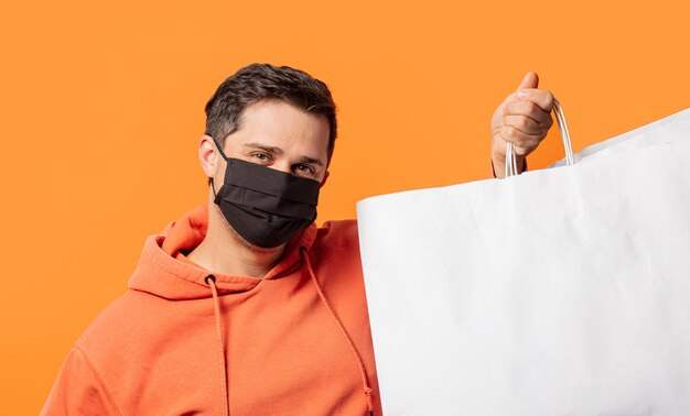 Guy in face mask and with shopping bags on orange