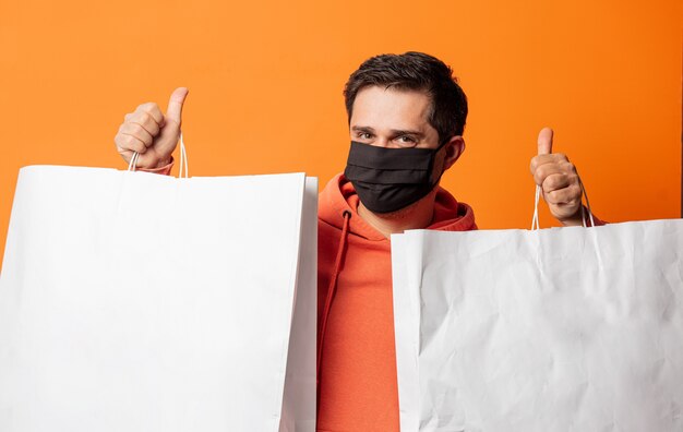 Ragazzo in maschera e con le borse della spesa sull'arancia