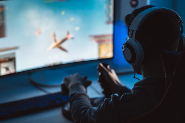 The guy gamer with headset playing video games on his personal computer