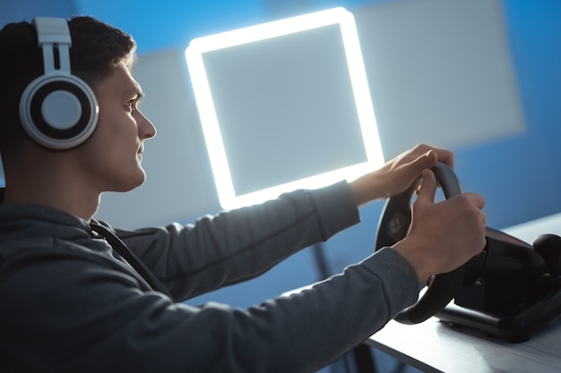 Парень-геймер с гарнитурой играет в видеоигры на своем персональном компьютере