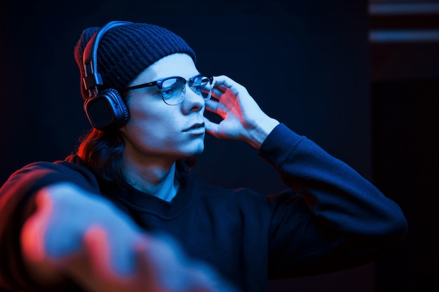 Guy geniet van de muziek. Studio opname in donkere studio met neonlicht. Portret van ernstige man