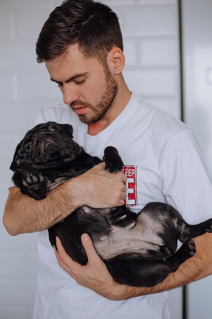 The guy gently hugs a pug dog