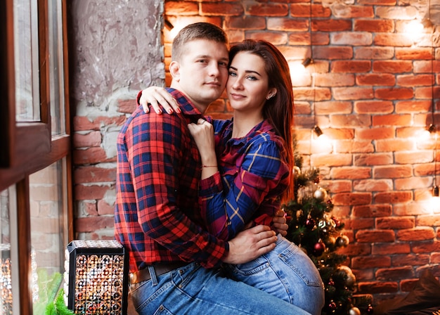 The guy and the girl are hugging at the window. A couple in love rejoices each other on New Year's Eve. New year love story