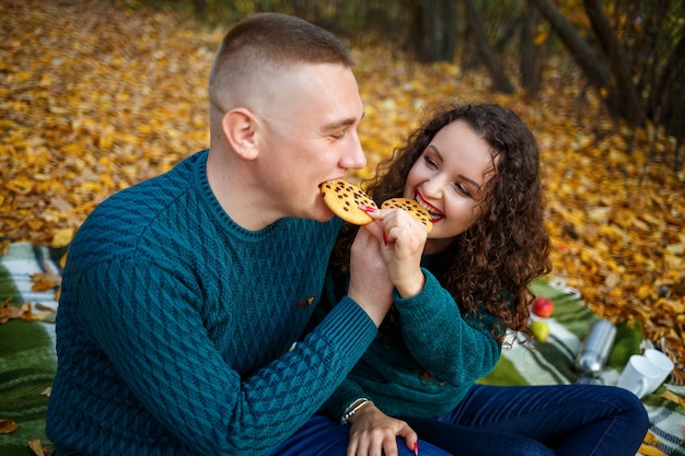 A guy and a girl in the autumn forest with cookies