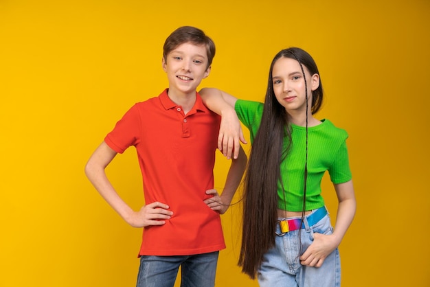 Guy and girl in bright Tshirts on yellow background girl put her hand on guy's