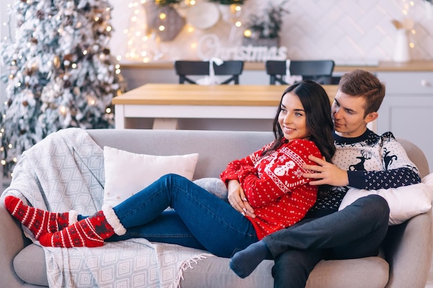 The guy and the girl celebrate Christmas A couple in love rejoices each other on New Year's Eve in a cozy home environment New Year's love story