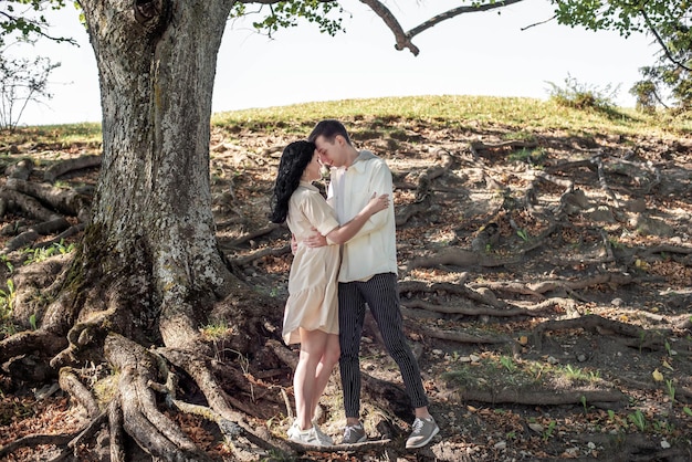 A guy and a girl, a couple in love stands under a tree and kisses