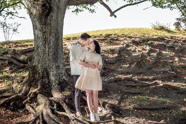 A guy and a girl, a couple in love stands under a tree and kisses