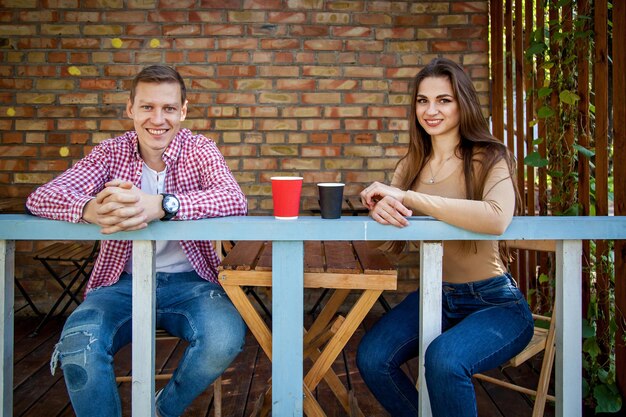 男と女がカフェのテラスの公園でコーヒーを飲む