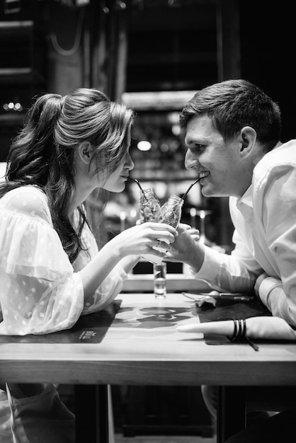 Guy and a girl have lunch in a cafe and drink cocktails
