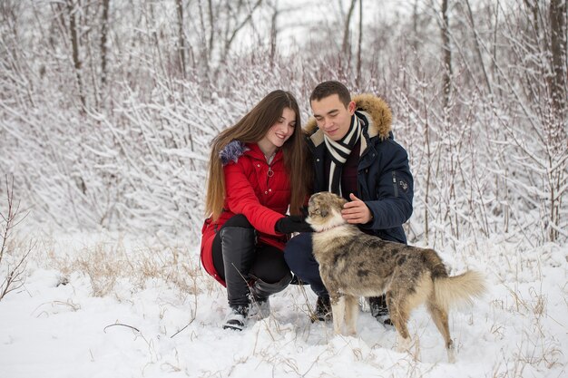 The guy and the girl have a rest in the winter woods. Husband and wife in the snow.