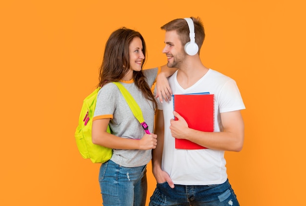 Guy and girl hold notebook university students on yellow background study with workbook