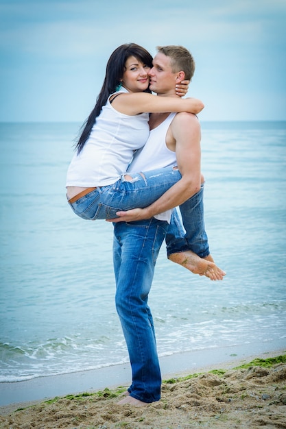 Парень и девушка в джинсах и белых футболках на берегу моря
