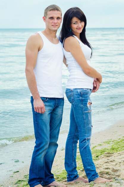 Guy and a girl in jeans and white t-shirts on the seashore