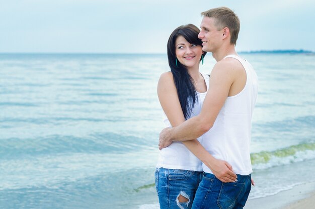 Парень и девушка в джинсах и белых футболках на берегу моря