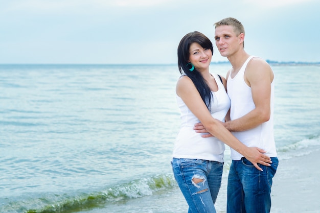 Guy and a girl in jeans and white t-shirts on the seashore