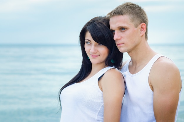 Guy and a girl in jeans and white t-shirts on the seashore