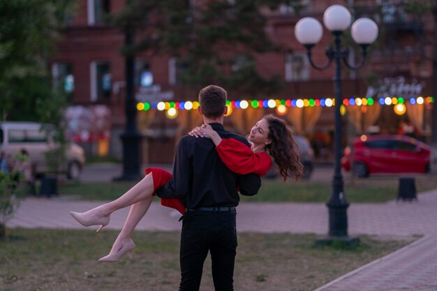 a guy and a girl kiss at sunset on the embankment near the river