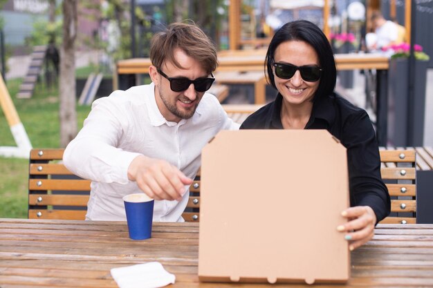 A guy and a girl opened a pizza box on the terrace in a restaurant