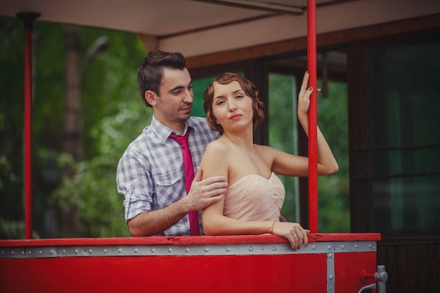 A guy and a girl in retro clothes vintage hairstyles are standing at the railing of the tram