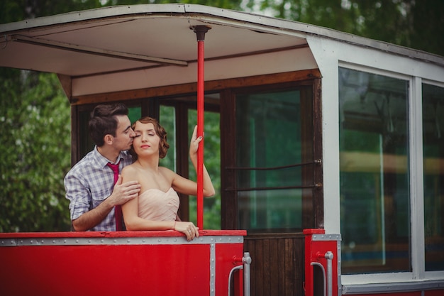 レトロな服のヴィンテージのヘアスタイルの男と女が路面電車の手すりに立っています。