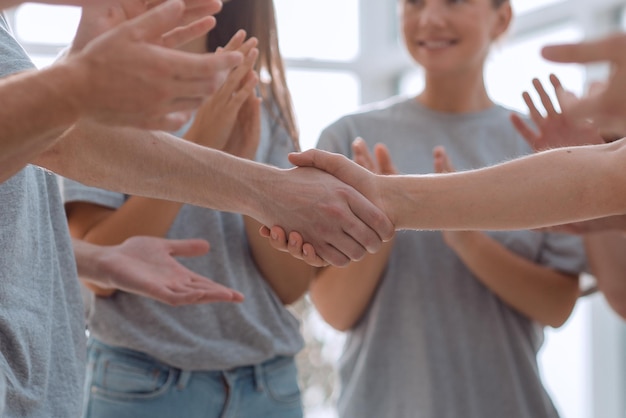 Guy and girl shaking hands sitting in a circle of friends