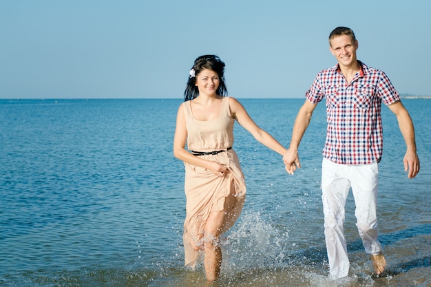 A guy and a girl walk along the seashore, swim in the water