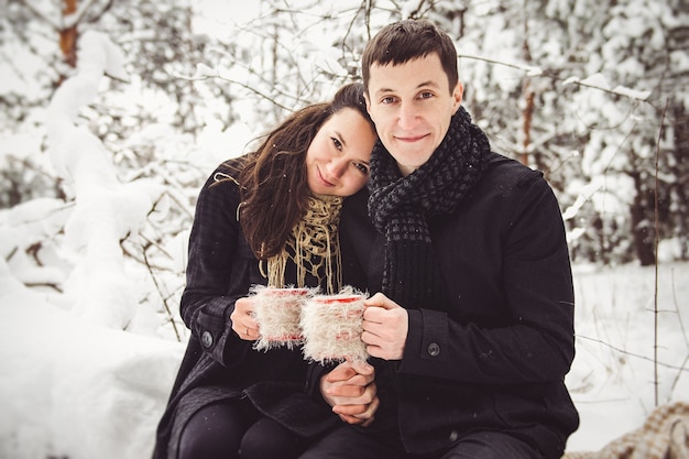 A guy and a girl in warm clothes and scarves on a walk in the snowy forest and in the field