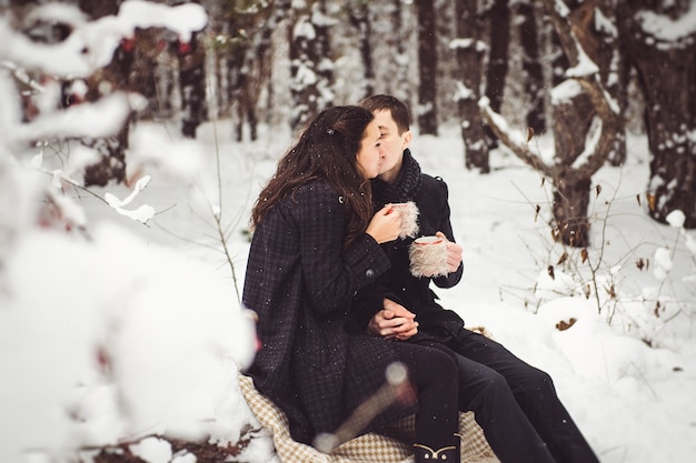 A guy and a girl in warm clothes and scarves on a walk in the snowy forest and in the field