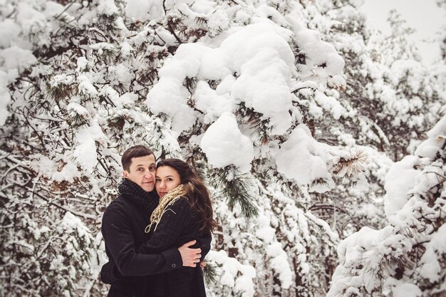 A guy and a girl in warm clothes and scarves on a walk in the snowy forest and in the field