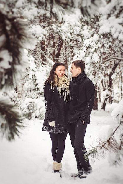 A guy and a girl in warm clothes and scarves on a walk in the snowy forest and in the field