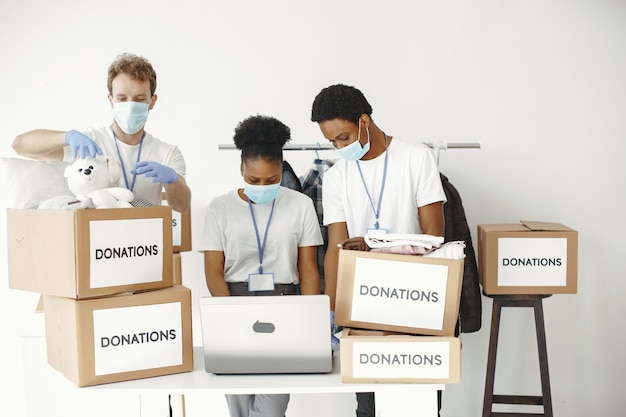 Guy and girl with check boxes Volunteers in masks with laptop Boxes with humanitarian aid